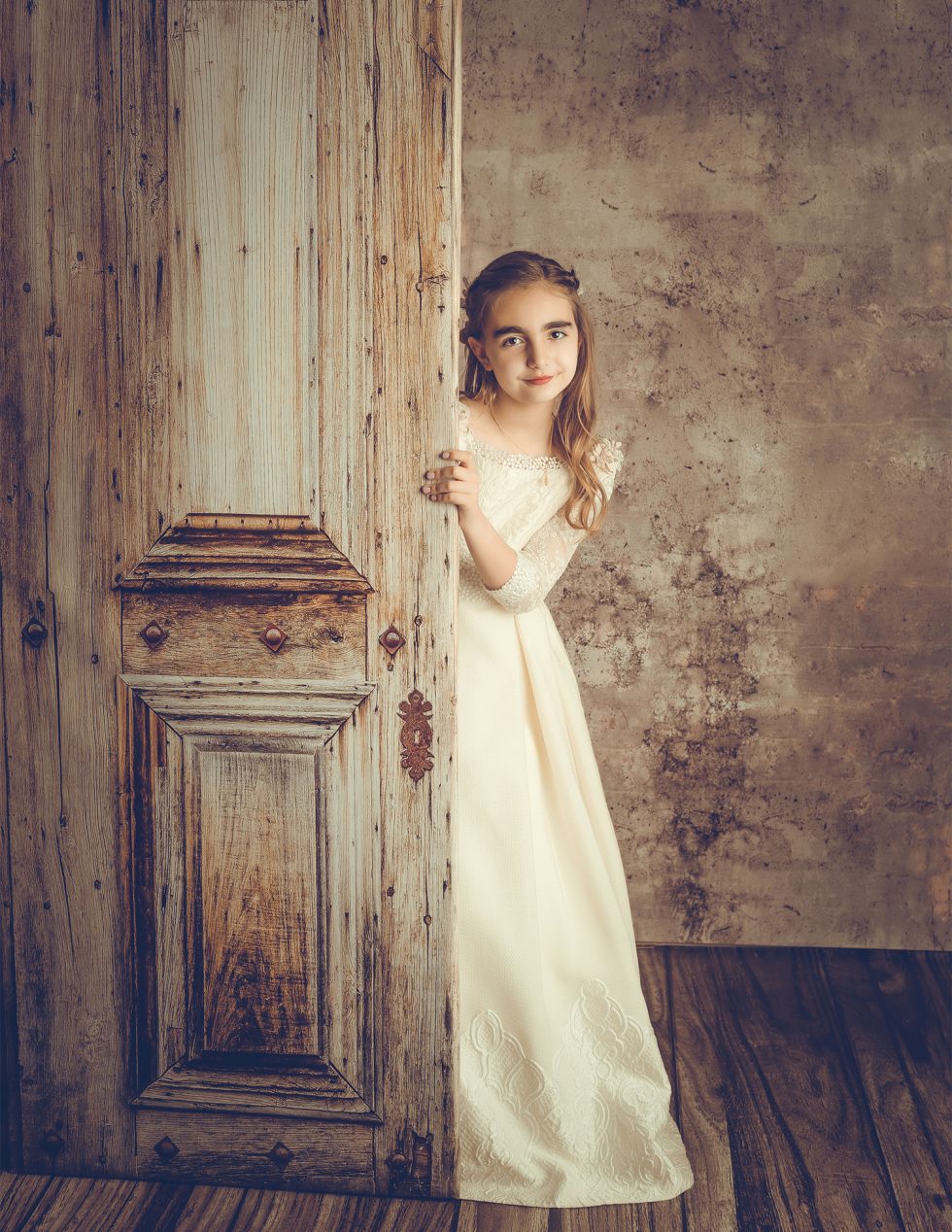 Niña sonriendo para su sesión de fotos de primera comunión.