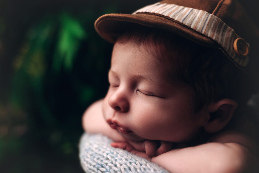 Bebé recién nacido dormido con gorra marrón, retrato artístico en primer plano en estudio de fotografía recién nacido en Getafe, Madrid