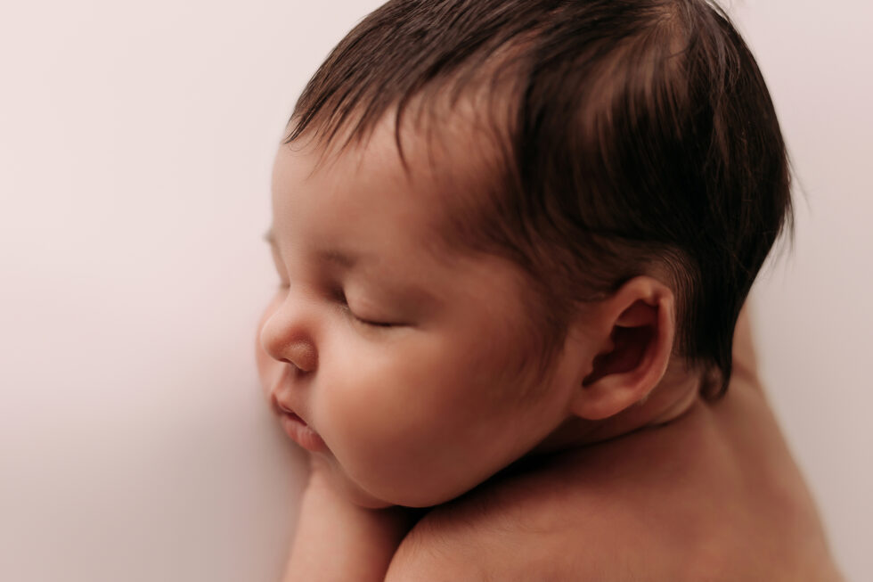 Bebé recién nacido dormido de perfil, retrato en primer plano sobre fondo claro en estudio de fotografía recién nacido en Getafe, Madrid