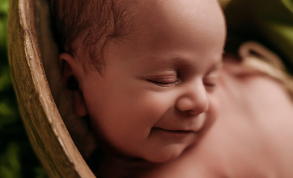 bebé recién nacido sonriendo en su sesión de fotos newborn