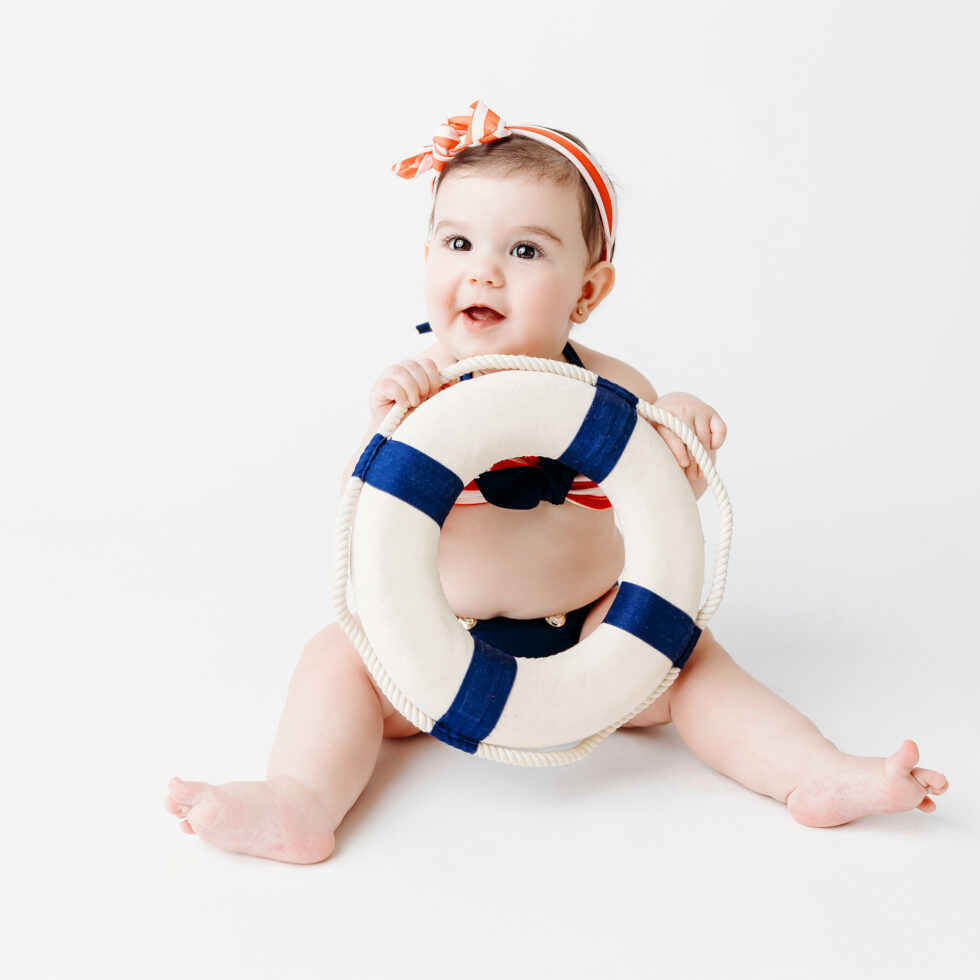 bebé sentado con flotador durante una sesión de fotos infantil en estudio con fondo blanco