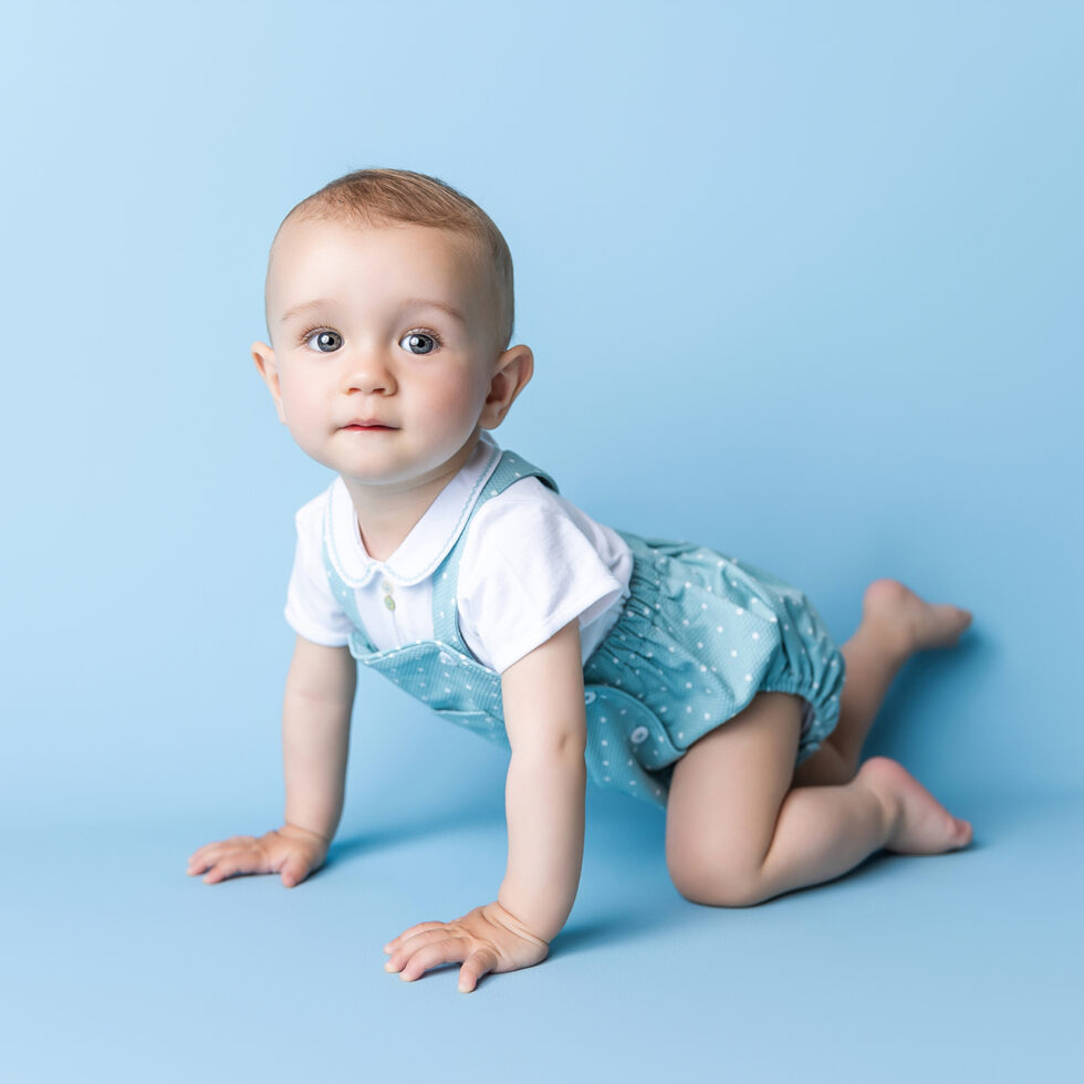 bebé gateando sobre fondo azul durante una sesión de fotografía de bebé en estudio en Getafe Madrid