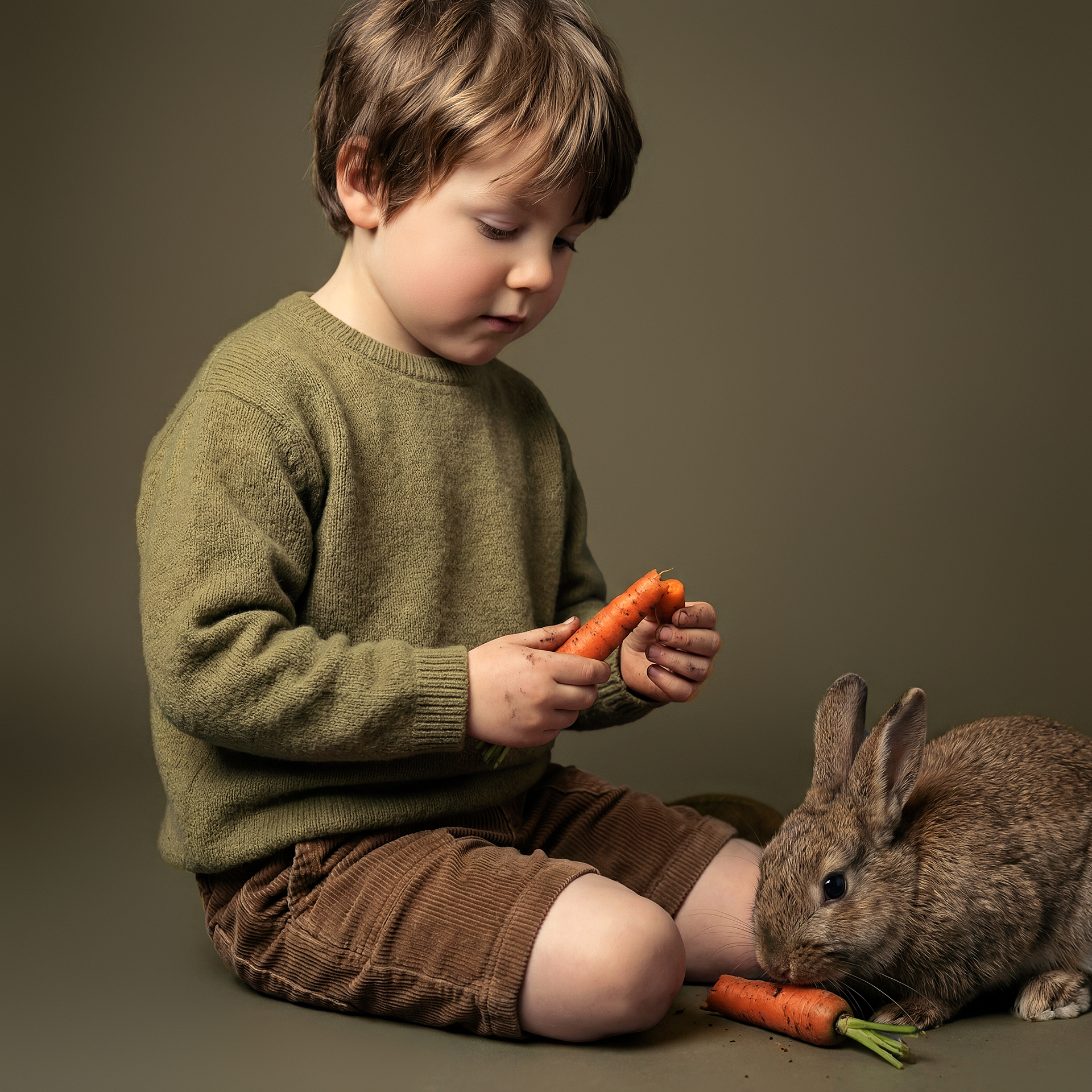 Niño dando una zanahoria a un conejo en fotografía infantil artística