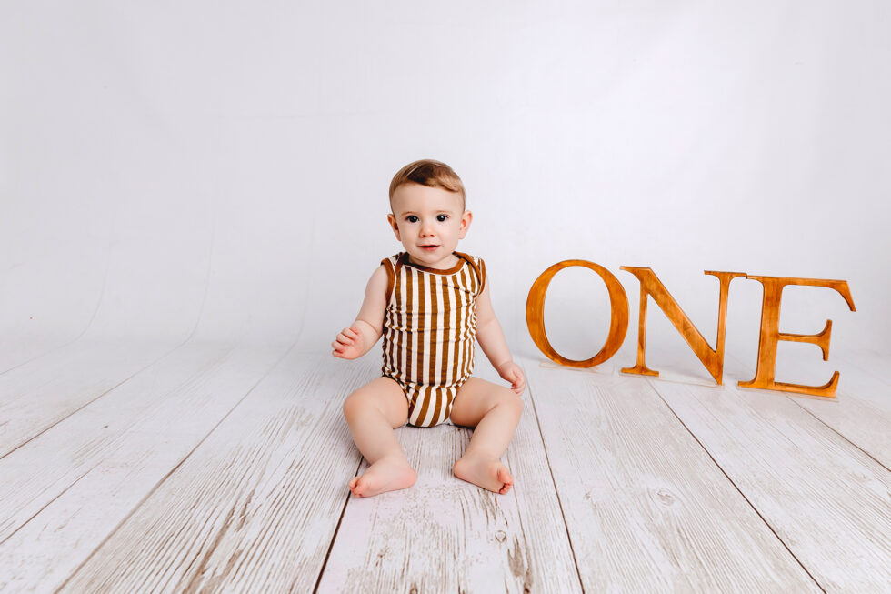 bebé celebrando su primer cumpleaños durante una sesión de fotos con letras one en estudio