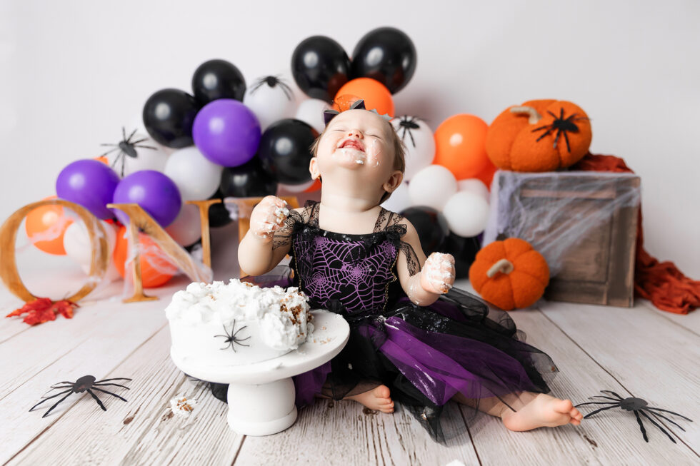 bebé disfrutando de una sesión smash cake temática de halloween durante su primer cumpleaños